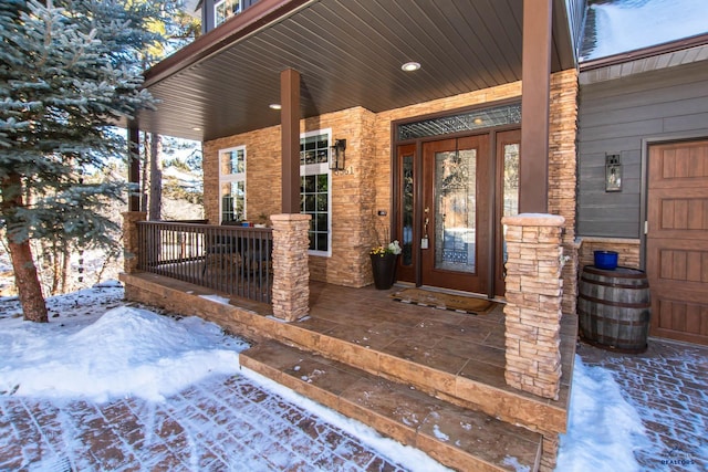 snow covered property entrance featuring a porch