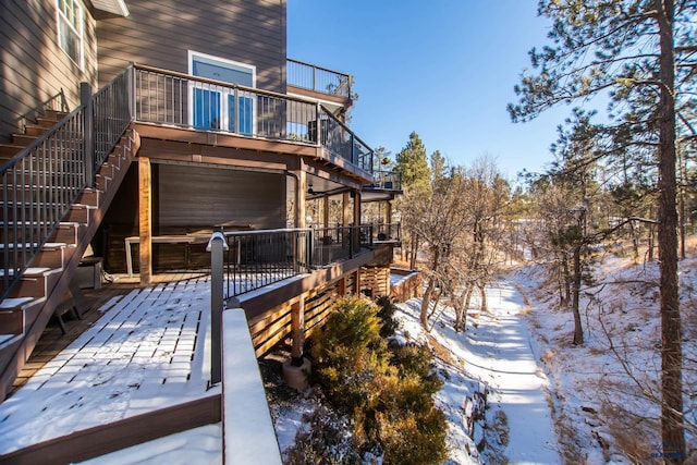 snow covered back of property featuring a wooden deck