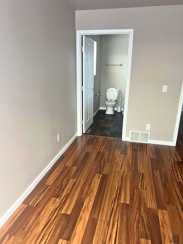 unfurnished bedroom with ensuite bath and dark hardwood / wood-style floors