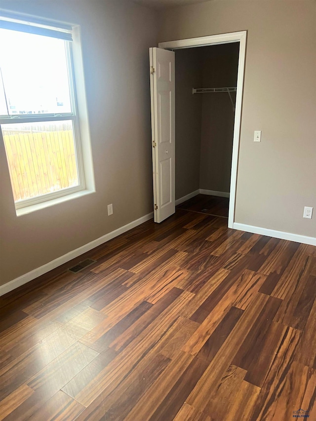 unfurnished bedroom with dark wood-type flooring and a closet