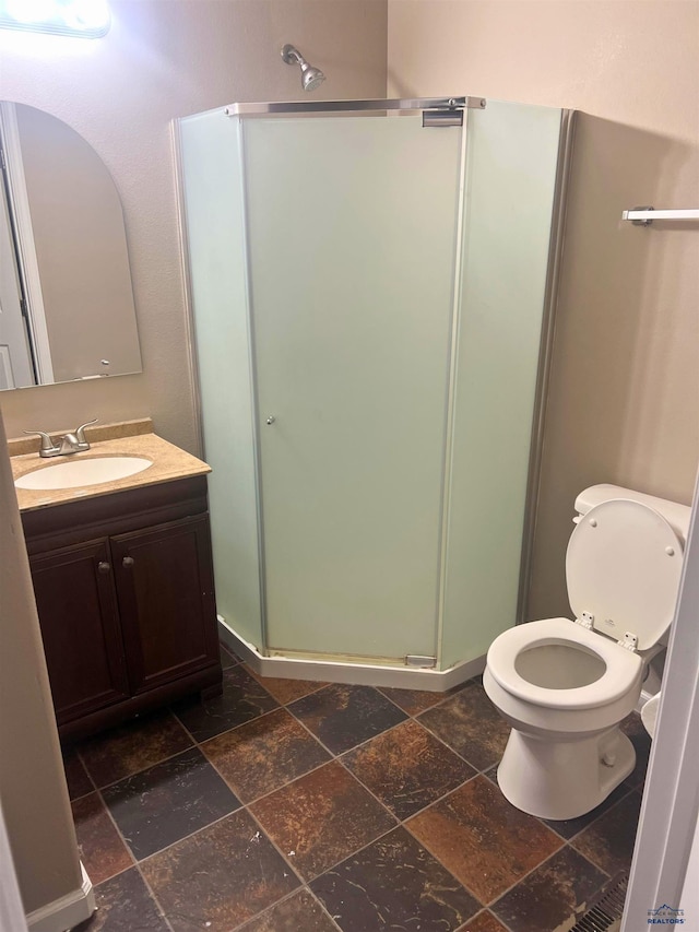 bathroom with vanity, toilet, and a shower with shower door