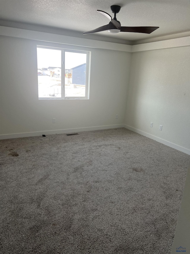 carpeted spare room featuring ceiling fan and a textured ceiling