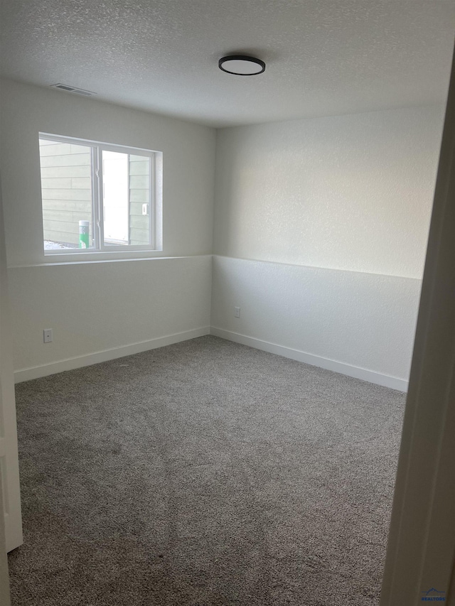 carpeted spare room featuring a textured ceiling