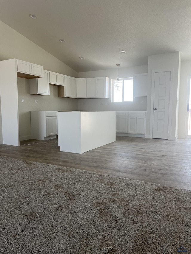 kitchen with white cabinetry, vaulted ceiling, dark wood-type flooring, and decorative light fixtures