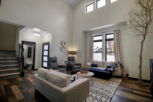 living room featuring dark wood-type flooring, an inviting chandelier, and a towering ceiling