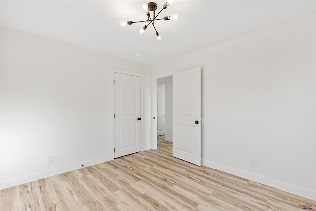 unfurnished room with an inviting chandelier and light wood-type flooring