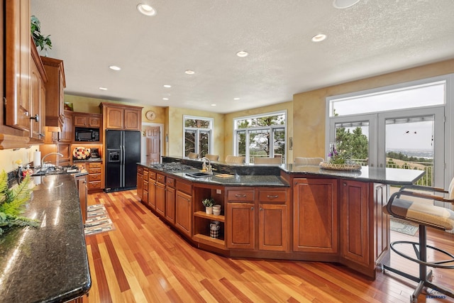 kitchen with a breakfast bar, dark stone countertops, a center island, black appliances, and french doors