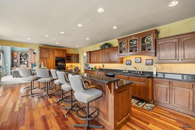 kitchen featuring sink, light hardwood / wood-style flooring, a kitchen breakfast bar, a kitchen island, and black appliances