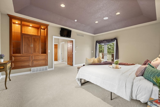 bedroom featuring light colored carpet, a raised ceiling, a textured ceiling, and french doors