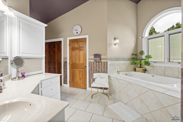 bathroom featuring a relaxing tiled tub, high vaulted ceiling, vanity, and tile patterned flooring