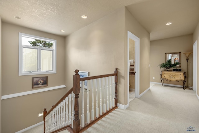 corridor featuring light carpet and a textured ceiling