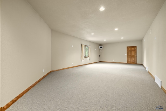 empty room with light carpet and a textured ceiling