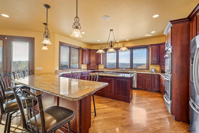 kitchen featuring a breakfast bar, pendant lighting, kitchen peninsula, a healthy amount of sunlight, and light wood-type flooring