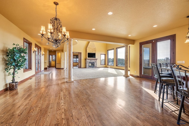 interior space featuring decorative columns, wood-type flooring, and a stone fireplace