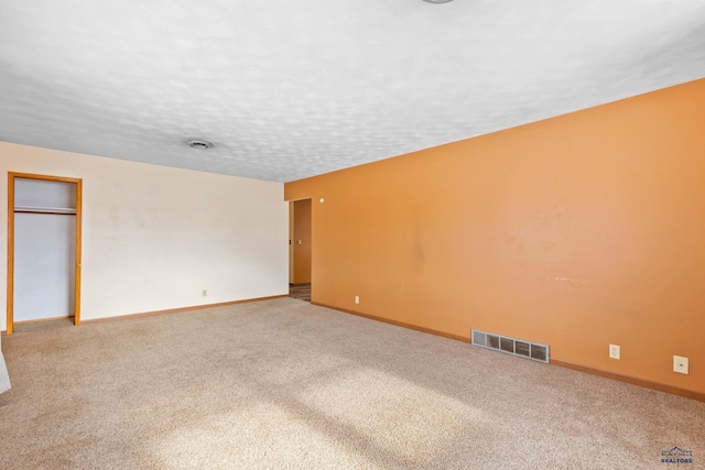 carpeted empty room featuring a textured ceiling