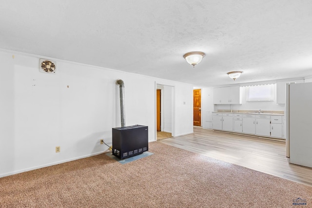 unfurnished living room with sink, light carpet, and a textured ceiling