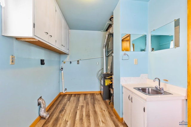 clothes washing area featuring sink, cabinets, and light hardwood / wood-style floors