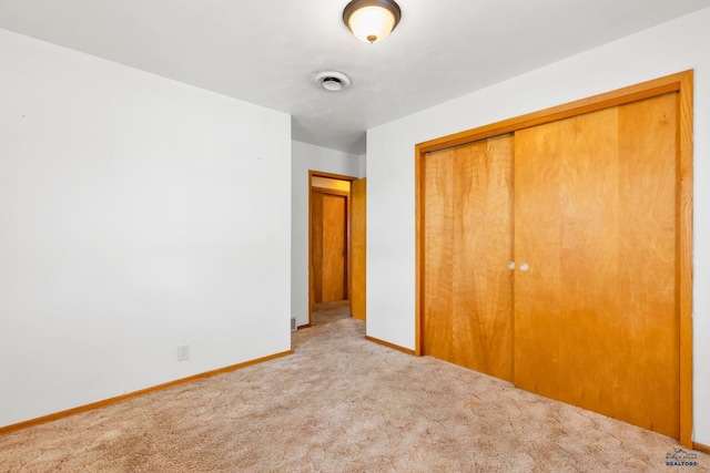 unfurnished bedroom with a closet and light colored carpet