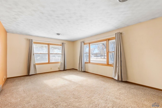 carpeted spare room with plenty of natural light and a textured ceiling