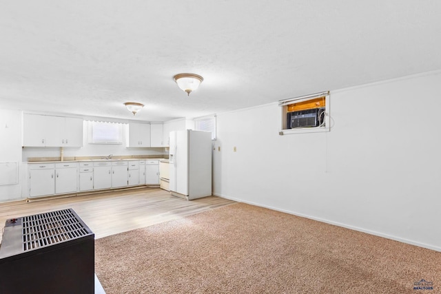 kitchen with white refrigerator with ice dispenser, light wood-type flooring, sink, white cabinetry, and a wall unit AC