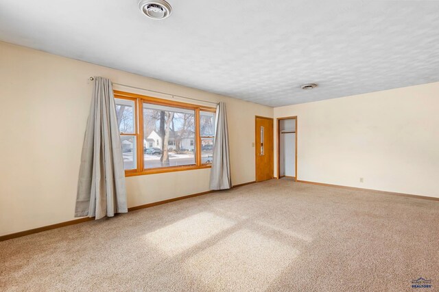 spare room featuring carpet floors and a textured ceiling