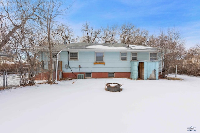 snow covered back of property featuring an outdoor fire pit and central air condition unit