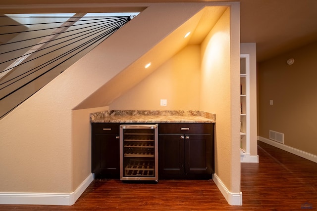 bar featuring dark brown cabinets, beverage cooler, light stone counters, and dark hardwood / wood-style floors