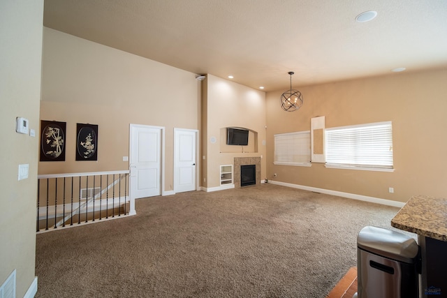 unfurnished living room with a tile fireplace, carpet flooring, and a towering ceiling