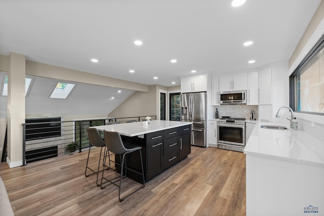 kitchen featuring sink, a center island, white cabinetry, light wood-type flooring, and stainless steel appliances