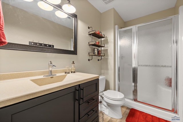 bathroom featuring hardwood / wood-style flooring, toilet, a shower with door, and vanity