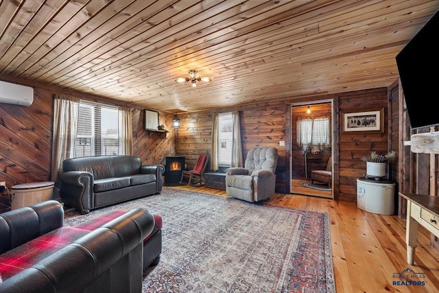 living room with a wall unit AC, a wood stove, light hardwood / wood-style floors, and wooden ceiling