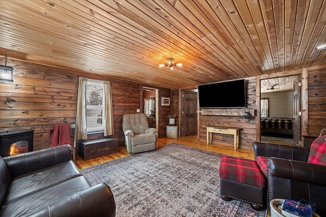 living room featuring hardwood / wood-style flooring, wood ceiling, a wood stove, and log walls