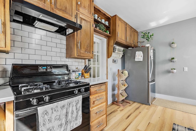 1016 W Blvd, Rapid City, SD 57701 - kitchen featuring black gas range, brown cabinets, freestanding refrigerator, light countertops, and exhaust hood