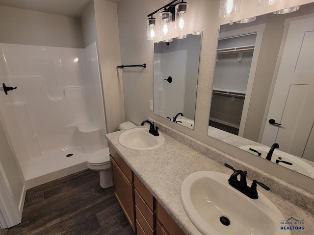 1154 Cobalt Dr, Rapid City, SD 57701 - bathroom featuring wood finished floors, a shower, toilet, double vanity, and a spacious closet