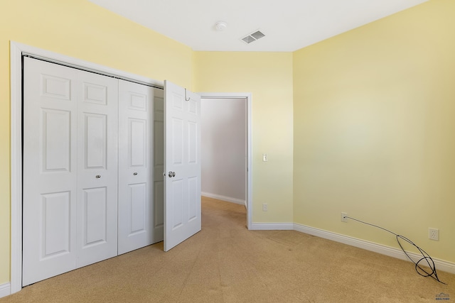 unfurnished bedroom featuring light carpet, a closet, visible vents, and baseboards