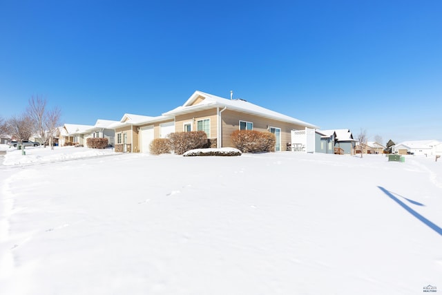 snow covered property with a garage and a residential view