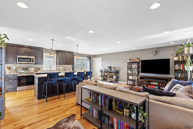 living area featuring light wood-style flooring, a textured ceiling, and recessed lighting