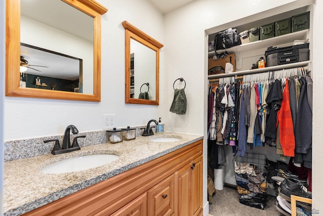 bathroom with a ceiling fan, a sink, a spacious closet, and double vanity