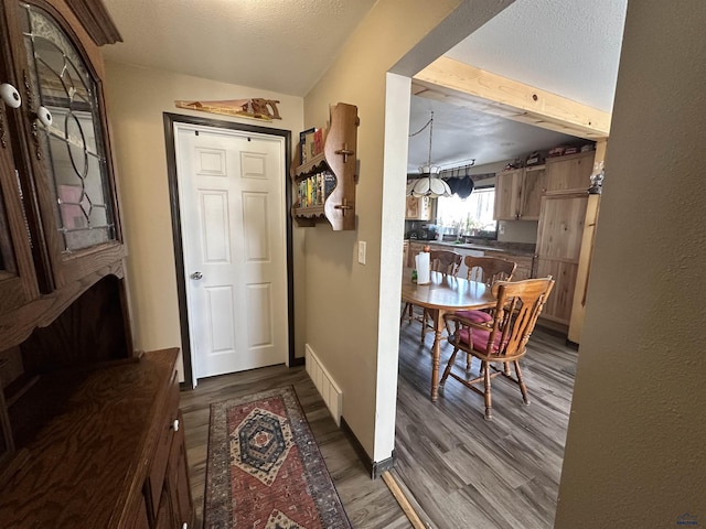 doorway to outside featuring baseboards, dark wood finished floors, and a textured ceiling