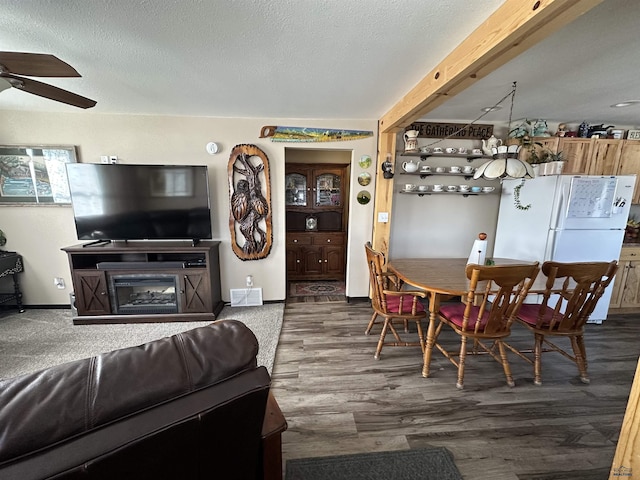 living room featuring a ceiling fan, visible vents, dark wood finished floors, and a textured ceiling