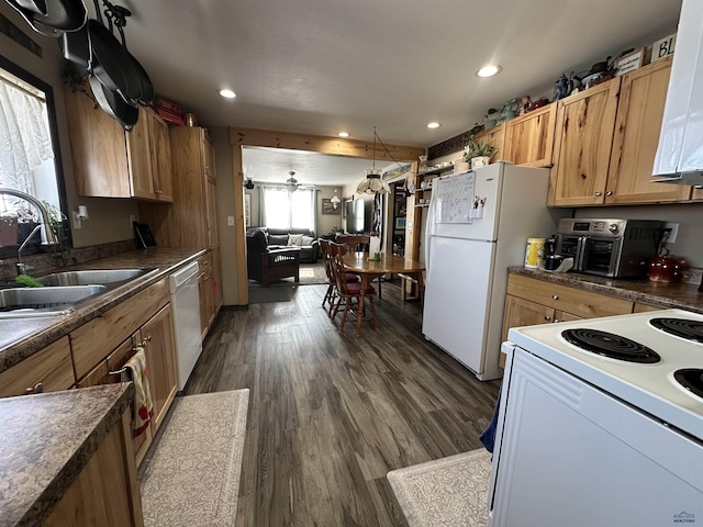 kitchen featuring white appliances, dark countertops, dark wood-style floors, a sink, and recessed lighting