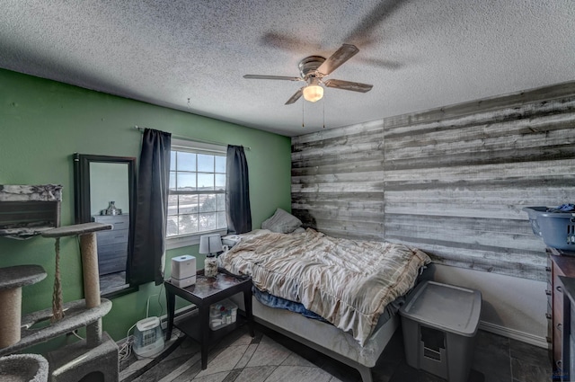 bedroom featuring ceiling fan, wooden walls, and a textured ceiling