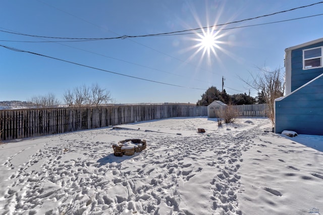 yard covered in snow featuring a shed and fence