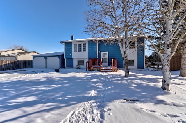 raised ranch featuring a garage and fence