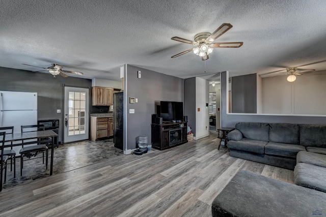 living area with baseboards, a textured ceiling, a ceiling fan, and wood finished floors