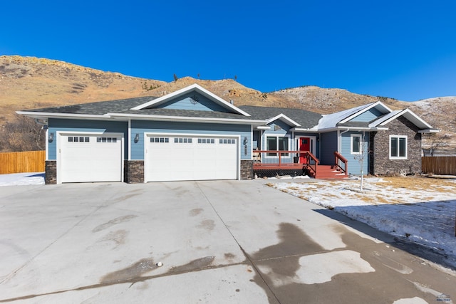 view of front facade featuring a garage, stone siding, driveway, and a mountain view