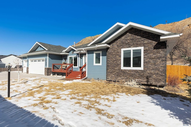 view of front of house featuring a garage, stone siding, and fence