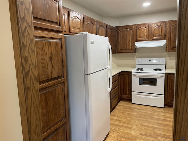 kitchen featuring light wood-style flooring, white appliances, light countertops, and under cabinet range hood