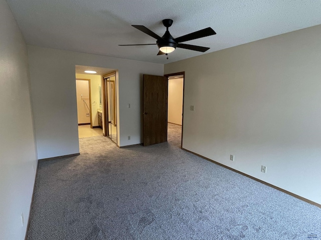 unfurnished bedroom with baseboards, a ceiling fan, light colored carpet, ensuite bath, and a textured ceiling