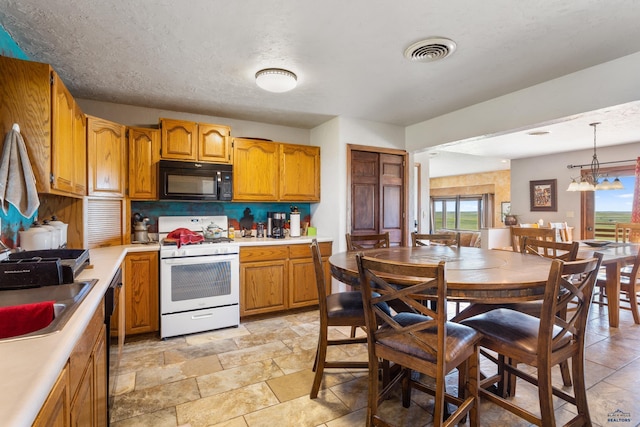 kitchen with visible vents, black appliances, light countertops, and decorative light fixtures